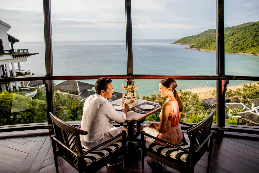 a man and woman sitting at a table with a view of the ocean.