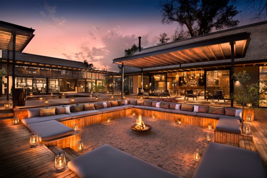 a patio with a fire pit surrounded by lounge chairs.