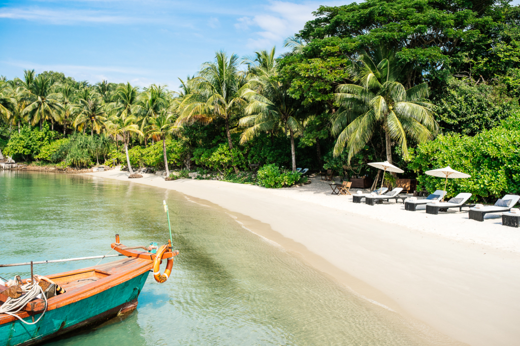 a boat is docked on the shore of a tropical beach.