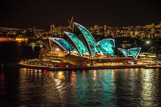 the sydney opera house lit up at night.
